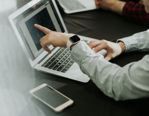 two people sitting at a table with laptops